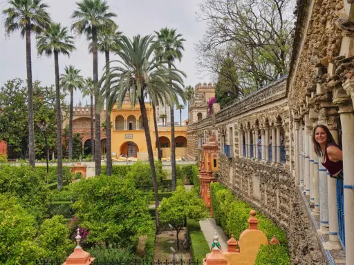 Ein Wahrzeichen von Sevilla: üppige Gärten, Palmen und eine Frau, die aus einem Säulengang schaut.