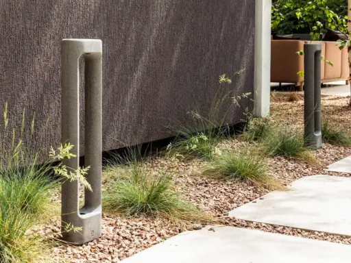 Deux bornes d'éclairage modernes en béton, bordant un chemin. L'ensemble respecte la norme éclairage lux pour un jardin contemporain.