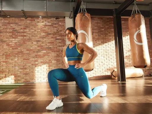 Frau macht Ausfallschritte im Fitnessstudio. Sie trainiert hart, um ihre Ziele zu erreichen, ohne sich über kreatin nebenwirkungen frauen Gedanken zu machen.