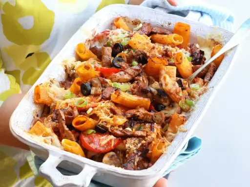 Pyszna zapiekanka z mięsem mielonym, makaronem rigatoni, oliwkami i pomidorami, posypana serem i szczypiorkiem.