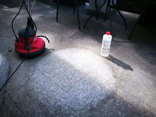 Czym czyścić granit płomieniowany? Na zdjęciu widać maszynę czyszczącą i butelkę z preparatem do czyszczenia kamienia.