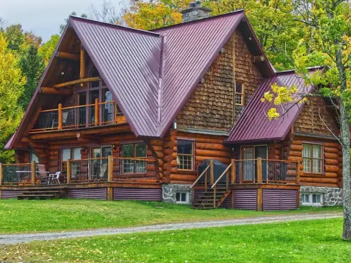 Chalet en bois rond avec toiture métallique, entouré d'arbres aux couleurs d'automne. Un exemple de développement durable bâtiment, alliant esthétique et respect de l'environnement.