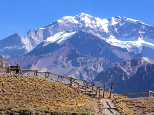 Aconcagua, najwyższy szczyt w Ameryce Południowej, góruje nad surowym krajobrazem. Ścieżka z drewnianym ogrodzeniem prowadzi na wzgórze.