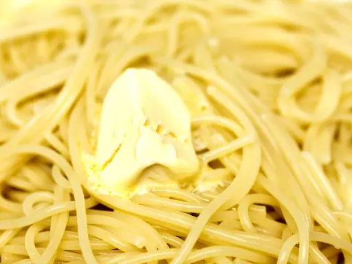 Un piatto di pasta in bianco fumante, con una generosa porzione di burro che si scioglie lentamente.