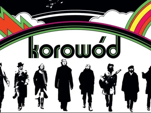Grupa ludzi w czerni, jakby z dwóch morgi słońca, idzie pod tęczą. Napis "korowód" sugeruje, że to oni śpiewają.