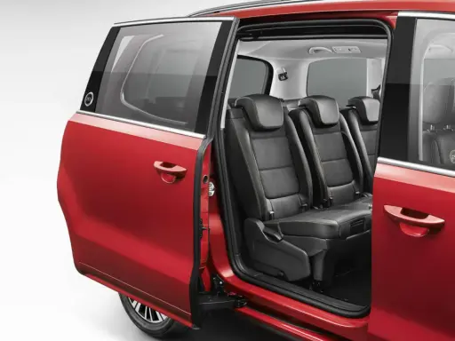 Interior de coches con puertas correderas rojas, mostrando asientos de cuero negro y detalles de costura.