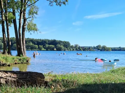 Słoneczny dzień nad jeziorem Pławniowice. Ludzie kąpią się i relaksują na dmuchanych zabawkach.