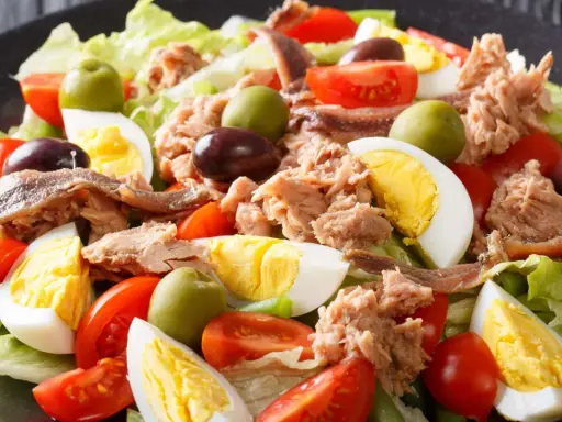 Ein bunter Nizza Salat mit Thunfisch, Ei, Tomaten, Oliven und Sardellen auf knackigem Salatbett.