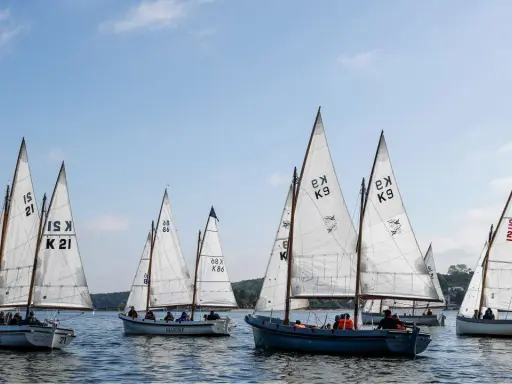 Segelboote mit weißen Segeln und Nummern wie "21" und "K9" auf dem Wasser, ein Teil der Veranstaltung "wm kiel".
