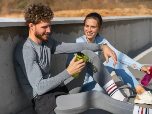 Ein Mann und eine Frau sitzen nach dem Sport und reden. Sie fragen sich, wie lange Pause nach Halbmarathon sinnvoll ist.
