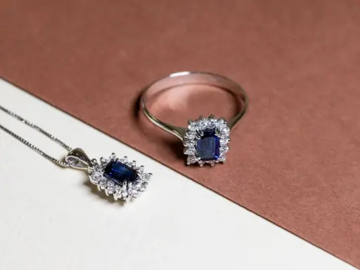 Anello e pendente con un intenso rubino blu al centro, circondato da piccoli diamanti scintillanti.
