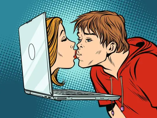 Chłopak i dziewczyna całują się przez ekran laptopa, symbolizując cyber sex i wirtualną bliskość.