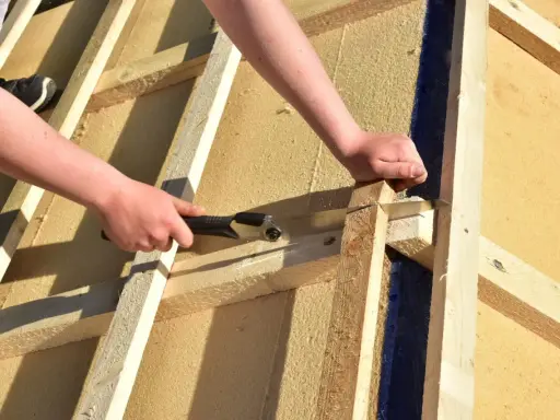 Holzfaserplatte Fassade: Hände sägen Holz für den Hausbau.