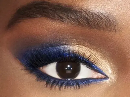 Ojo con un audaz maquillaje de ojos azul y dorado. Delineador azul vibrante y sombras doradas brillantes resaltan la mirada.