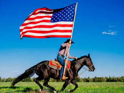 Kowbojka na czarnym koniu niesie flagę USA. To obraz wolności i dzikiego zachodu, pełen ciekawostek o Ameryce.