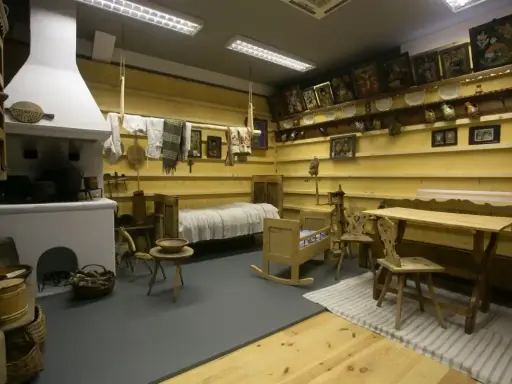 Wnętrze izby w muzeum w Szczawnicy: piec, łóżko, kołyska, stół i krzesła.