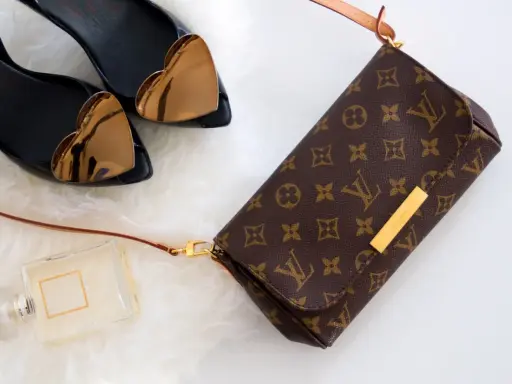 Torebka Louis Vuitton, czarne buty z sercami, perfumy na białym tle.