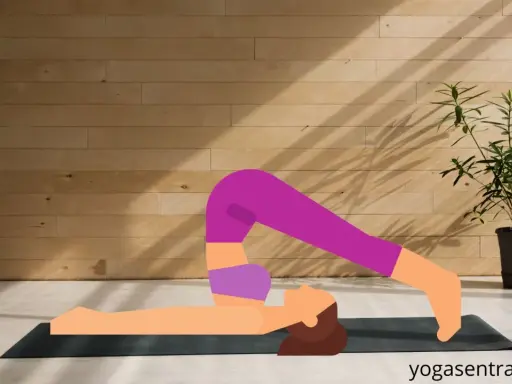 En person utför plogen yoga på en matta framför en trävägg.