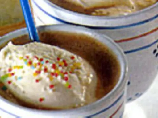 Zwei Becher mit cremigem Vanilleeis, bestreut mit bunten Streuseln. Ein köstliches Eiscafe Rezept für heiße Tage.