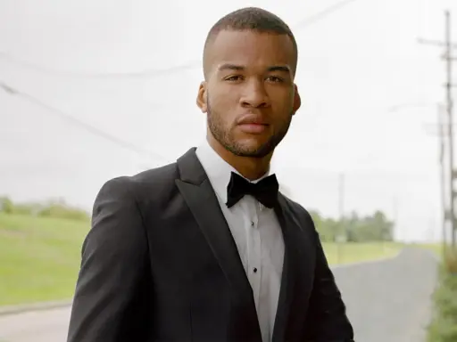 A man in a black tuxedo with a bow tie, ready for black tie weddings.