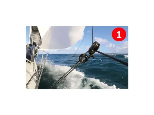 Le fonctionnement poulie est visible sur ce voilier naviguant sur une mer agitée. Les cordages tirent la voile blanche.