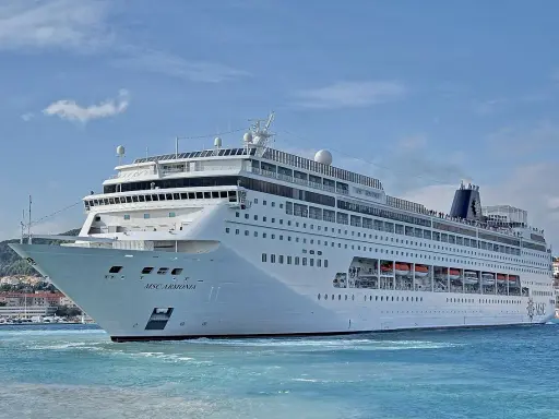 La MSC Armonia, con la sua impressionante lunghezza, solca le acque azzurre vicino a una costa collinare.