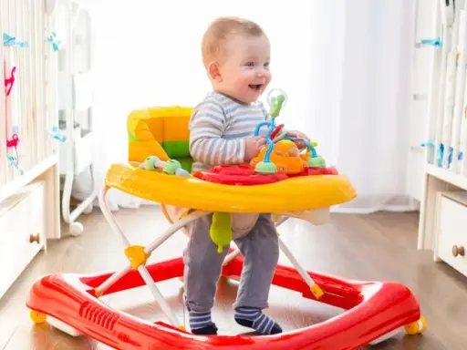 Uśmiechnięty maluch w chodziku bawi się zabawkami. Od kiedy chodzi, świat jest dla niego jeszcze ciekawszy!