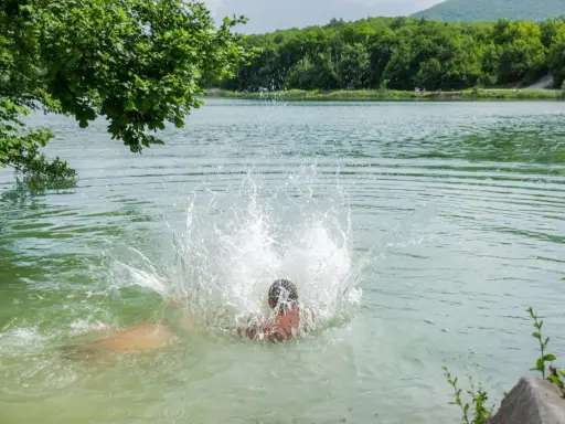 Osoba skacze do jeziora, tworząc duży plusk. Może to być początek przygody, która zakończy się wysypką po kąpieli w jeziorze.