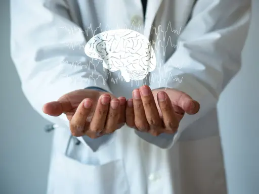 Dłonie lekarza w białym kitlu unoszą cyfrowy mózg z liniami EKG. Może to symbolizować diagnozę i leczenie chorób neurologicznych, np. i69 kod choroby.