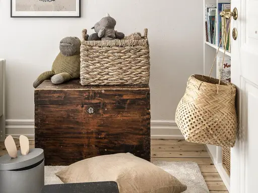 Cesti di vimini per idee arredare con stile: un cesto intrecciato sopra un baule antico, un altro appeso alla porta.