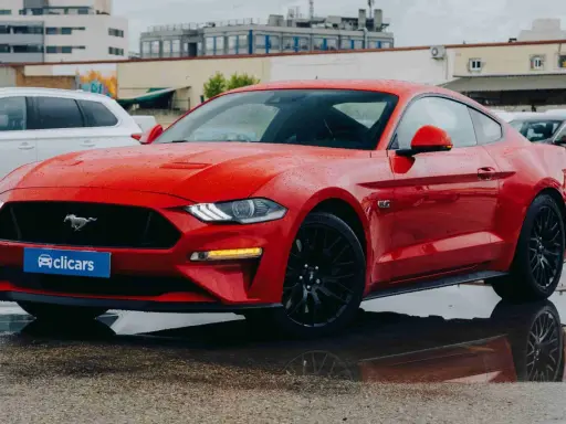 Un deportivo rojo, que es un coche coupe, brilla bajo la lluvia.