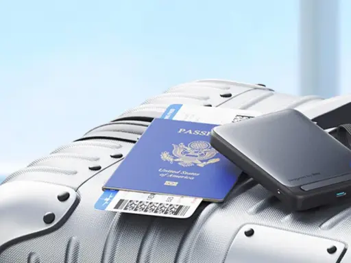 En powerbank, pass och flygbiljett ligger på en resväska, redo för resan med flygplan.