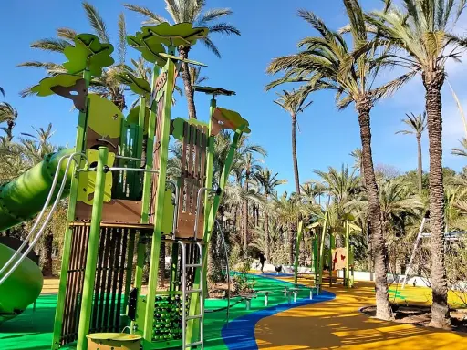 Parque el Palmeral con juegos infantiles coloridos y palmeras altas bajo un cielo azul.
