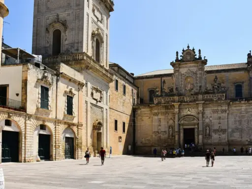 Piazza del Duomo a Lecce, un assaggio di cosa vedere a Lecce in un giorno: la cattedrale barocca e il campanile svettano sotto il sole.