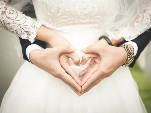 Manos formando un corazón sobre el vestido de novia, símbolo de una boda de platino.