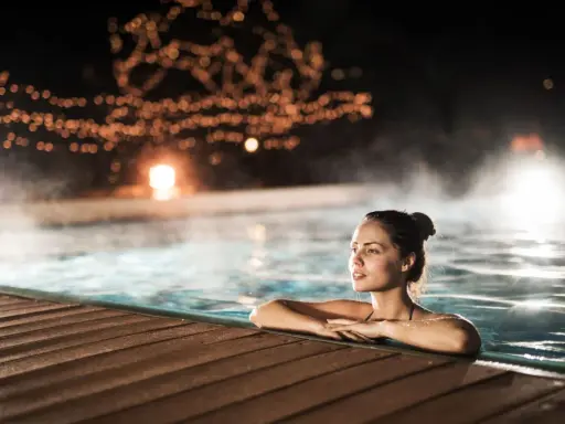 Entspannter Abend in den Thermen NRW. Eine Frau genießt das warme Wasser, umgeben von stimmungsvoller Beleuchtung und Dampf.