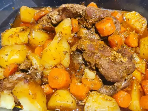 Pyszna karkówka po cygańsku z ziemniakami i marchewką w aromatycznym sosie. Danie wygląda na bardzo sycące i domowe.