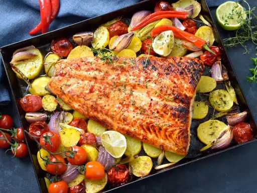 Pescado al horno con patatas, cebolla y tomate, asado a la perfección con hierbas frescas y un toque de limón.