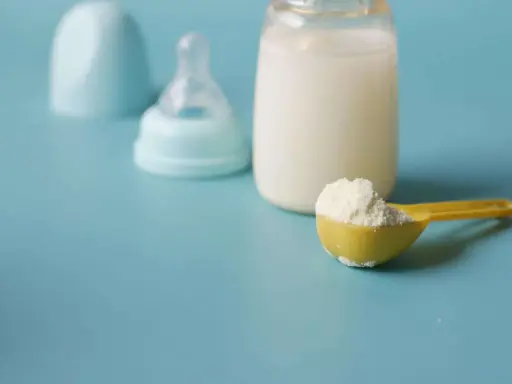 Biberon con latte, tettarella e misurino di latte in polvere, per capire quanto deve mangiare un neonato di 3 mesi.