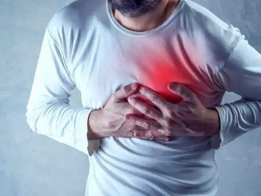 Mężczyzna trzyma się za klatkę piersiową, gdzie widoczny jest czerwony obszar bólu.