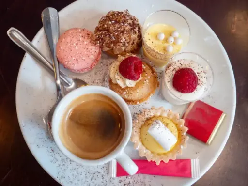 Assortiment de spécialités culinaires parisiennes : macarons, éclairs, tartellettes, verrines et café. Un délice pour les yeux et les papilles.