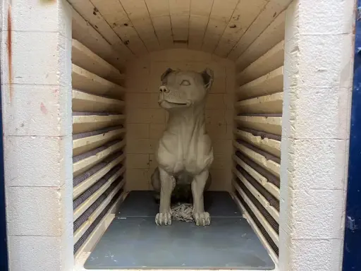 En lerhund sitter redo för bränning i en ugn.