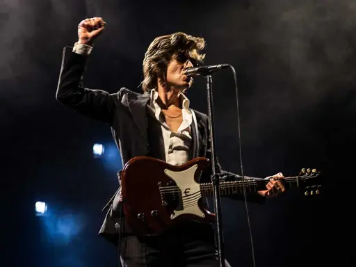 Alex Turner från Arctic Monkeys, med knuten näve i luften, spelar gitarr på scen i Stockholm.