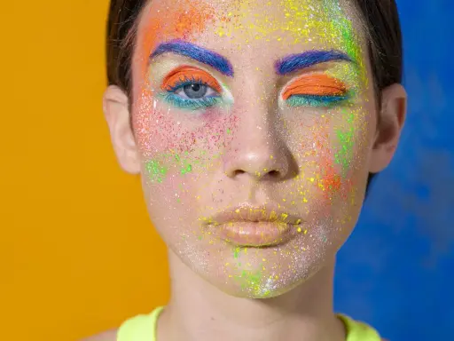 Rostro con maquillaje vibrante y purpurina. ¿Cómo quitar la purpurina de la cara? Este look es un desafío.