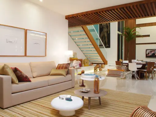 Elegantes salones marrones y beige con sofá, mesas auxiliares, alfombra a rayas y una escalera moderna.