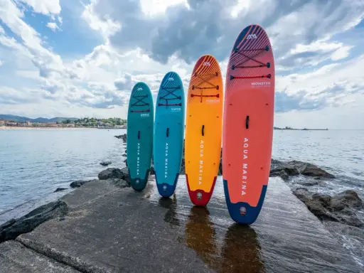 Cztery deski SUP stoją na kamiennym pomoście. Dwie z nich to sup dwuosobowy, idealne na wspólne wodne przygody.