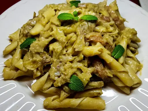 Un piatto invitante di pasta con carciofi, condita con erbe fresche, pronta per essere gustata.