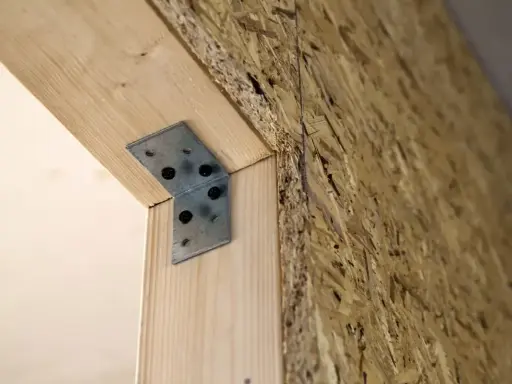 Metalowy kątownik wzmacnia połączenie drewna z płytą OSB, przygotowując konstrukcję pod tynk.