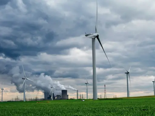 Windräder und ein Kraftwerk mit Dampf, Beispiele für regenerative Energien im Kontrast zur konventionellen Stromerzeugung.