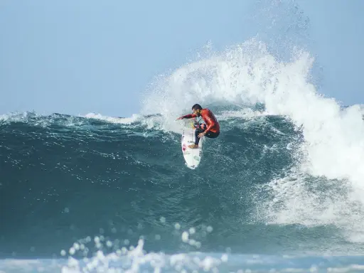 Surfer in rotem Neoprenanzug meistert eine riesige Welle beim Mauritius Surf.